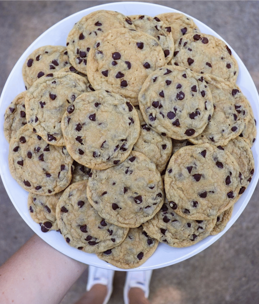 A perfect, classic chewy chocolate chip cookie broken open to show its soft, gooey center and melted chocolate chips, with crispy, golden-brown edges.